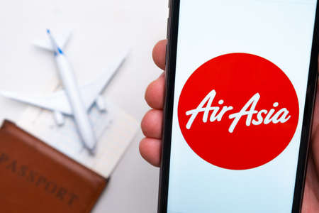 AirAsia Airline on the mobile phone screen with a plane, passport and boarding pass on the background. The concept of the airlines mobile application. November 2021, San Francisco, USAのeditorial素材