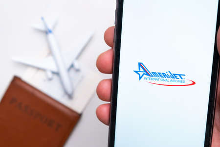AmeriJet International Airline app on a smartphone screen with a plane and passport on the background. The concept of travel app. November 2021, San Francisco, USAのeditorial素材