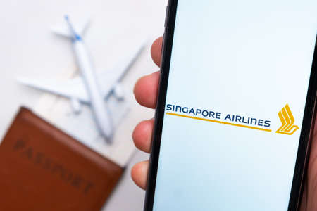 Singapore Airlines app on the cell phone screen in mans hand with plane, boarding pass and passport on the background. The concept of the airlines mobile application. November 2021, San Francisco, USAのeditorial素材