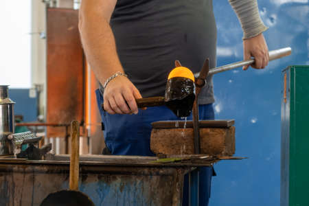 Manual glass production by glassblowing by worker at the factory.