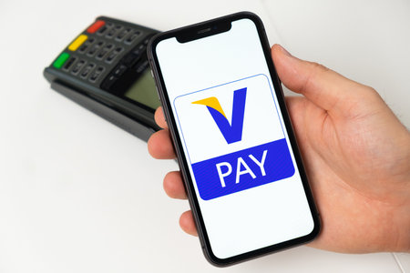V Pay debit electronic payment system. A man pays for goods and services using a mobile application, smartphone and POS payment terminal. November 2021, San Francisco, USAのeditorial素材