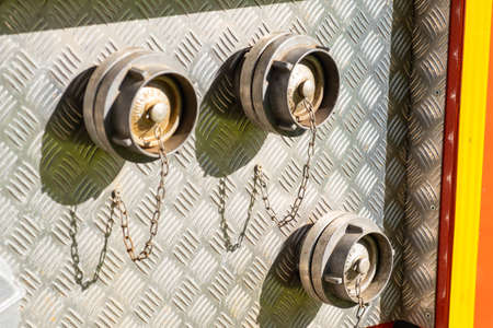 Closed with corks hose plugs on grey metal side of contemporary fire truck standing at station on sunny day extreme close viewの写真素材
