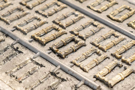 Small metal decorative details rows molded in high precision cast form in brightly lit production plant workshop extreme close viewの写真素材