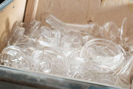 Broken transparent glass pieces prepared for recycling and different items making in large wooden crate extreme close viewの写真素材