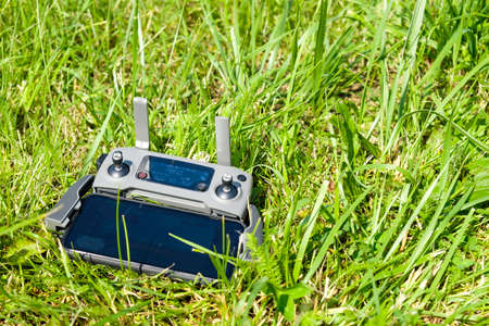 The drone console controller with the mobile phone is lying on the grass. Aerial photography of nature.のeditorial素材