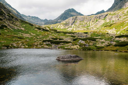 Beautiful lake in High Tatra mountains with stones in the middle and clouds reflections on water