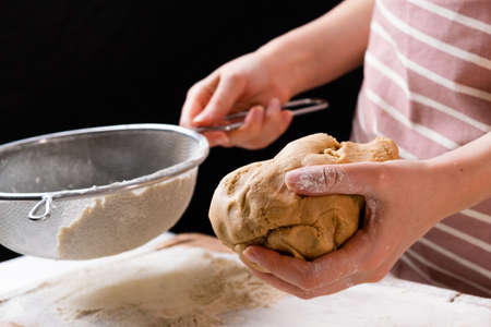 Close up woman sifts wheat flour through a sieve into mixing bowl for dough preparation for cake and...