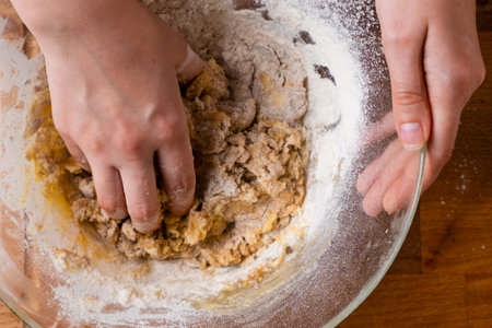 Close up of woman baker hands kneading the dough in the mixing bowl. Homemade pastry for cakes or cookies.の写真素材