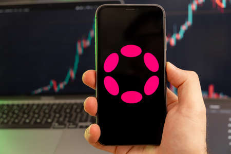 Polkadot DOT cryptocurrency on the screen of a smartphone in mans hand with a growing trend on the...