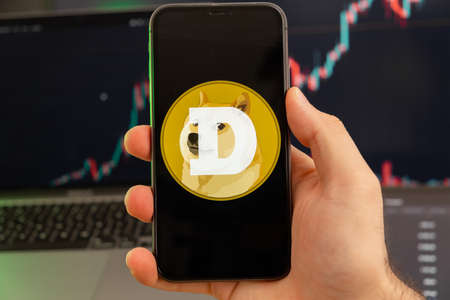 Dogecoin DOGE app of cryptocurrency stock market analysis on the screen of mobile phone in man hands...