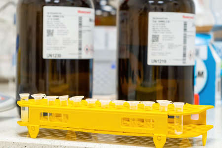 Microcentrifuge plastic tubes with the sample in the rack on the background of the bottle with...