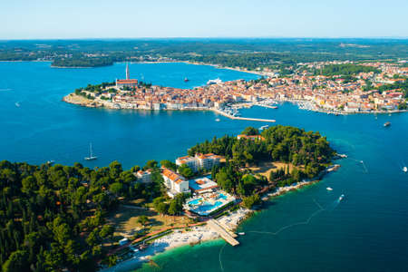 Rovinj surroundings with church of St. Euphemia near Adriatic sea. Villas with swimming pools and buildings with red roofs at bright sunlight. Aerial viewの写真素材