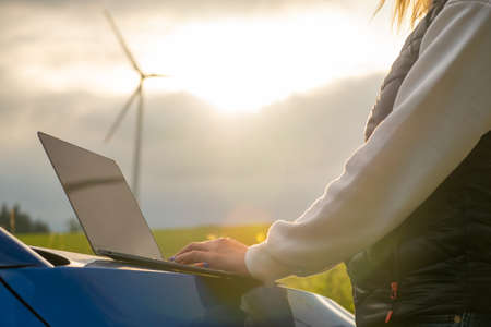 Female engineer checking the stability work of windmill with laptop in the field at sunlight. Green energy of futureの写真素材