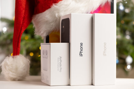 Iphone, Airpods Pro, Apple watch, iPad Pro boxes with Santa Claus hat and Christmas tree on the background. Gifts for Happy New Year concept. October 2022, Prague, Czech Republicのeditorial素材