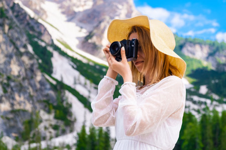 Travel photographer wearing a white dress and hat taking a picture of the amazing Dolomites Alps, Italyの写真素材