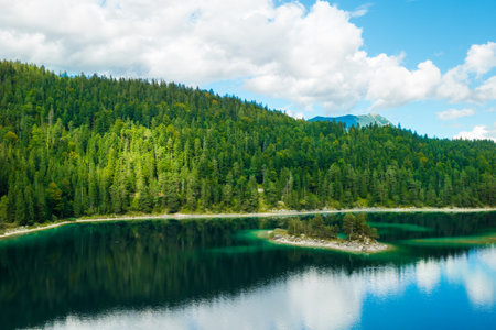 Mountains with spruce trees and clouds are reflected in a forest river. Summer landscape of a riverside.の写真素材