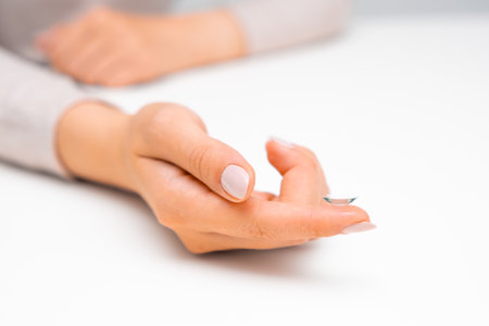 Woman hand holding eye contact on the white surface.の写真素材