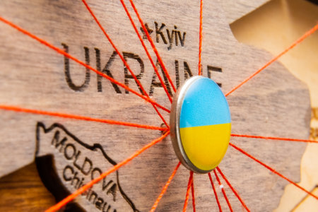 Ukraine flag on the pushpin with red thread showed the paths of movement or areas of influence in the global economy on the wooden map. Planning of traveling or logistic concept. Network connection.の写真素材
