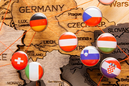 Germany, Czech Republic, Italy, Slovenia, Hungary, Switzerland, and Croatia flags on the pins connected with red thread on a wooden map. Marking visited places. Travel planning.の写真素材