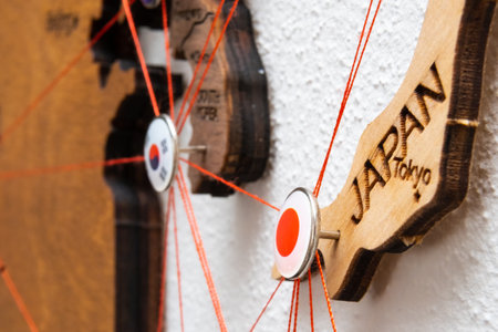 Japan flag on the pushpin with red thread showed the paths of movement or areas of influence in the global economy on the wooden map. Planning of traveling or logistic concept. Network connection.の写真素材