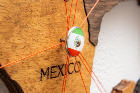 Mexico flag on the pushpin with red thread showed the paths of movement or areas of influence in the global economy on the wooden map. Planning of traveling or logistic concept. Network connection.の写真素材