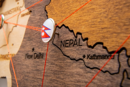 Nepal flag on the pushpin with red thread showed the paths of movement or areas of influence in the global economy on the wooden map. Planning of traveling or logistic concept. Network connection.の写真素材