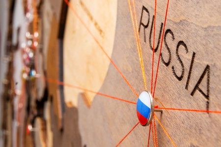 Russia flag on the pushpin and red threads on the wooden map. Travel or logistic routes. Influence in geopolitics and world economy.の写真素材