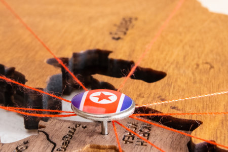 North Korea flag on the pushpin and red thread on the wooden map, close up. Mark of visiting places and planning of vacation and travel routes.の写真素材