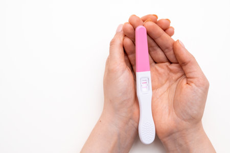 Positive pregnancy test in woman hands on the white background with copy spaceの写真素材