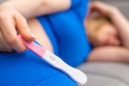 Upset young woman with a positive pregnancy test laying down on the sofa.の写真素材