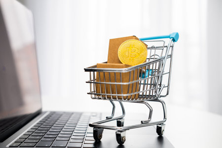 Bitcoins in a toy shopping cart on the laptop. Online shopping concept.の写真素材