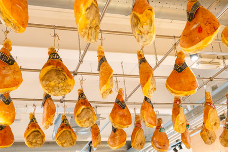 Jamon or leg of SErrano ham hanging from the ceiling in a supermarket.のeditorial素材
