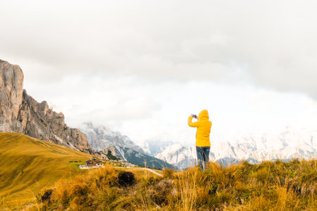 The tourist uses her smartphone to capture the scenic Alpine mountain meadows.の写真素材
