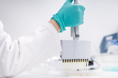 Scientist employs a multichannel pipette dispenser to load microplates for microbiological analysis.