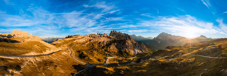 High stone columns of mountain massif of Tre Cime di Lavaredo at sunset. Battlement-like peaks under...