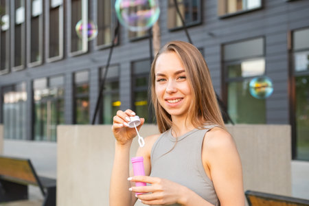 Portrait of happy young woman with flowing hair blows soap bubblesの写真素材