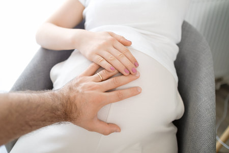 Mans and womans hands on the pregnant stomach. Expecting baby.の写真素材