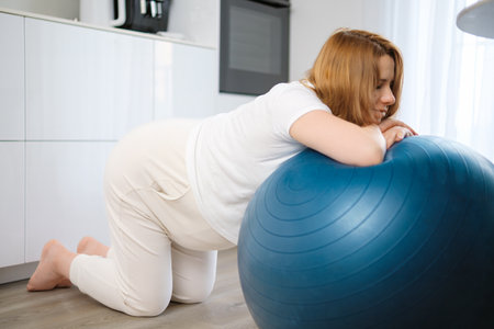 Pregnant woman with back pain doing exercises on the fit ballの写真素材