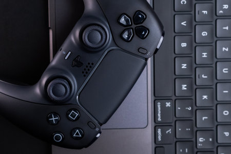 BERLIN , GERMANY - JANUARY 14 2024: Dualsense PS5 controller placed next to an Apple MacBook Pro...