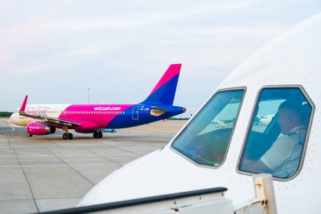 An airplane pilot is sitting in the cockpit and Wizzair aircraft on the background. January 2024, Prague, Czech Republicのeditorial素材