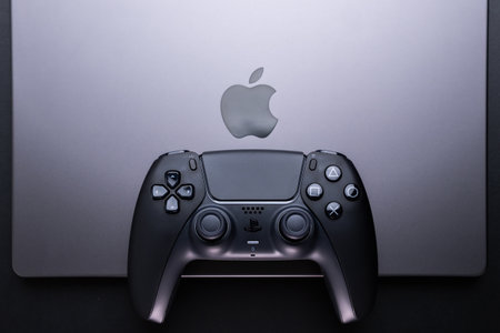 BERLIN , GERMANY - JANUARY 14 2024: Dualsense PS5 game controller placed near an Apple MacBook Pro...