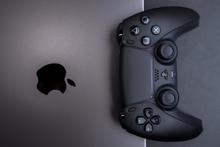 BERLIN , GERMANY - JANUARY 14 2024: Apple MacBook Pro Space Black laptop alongside a DualSense...