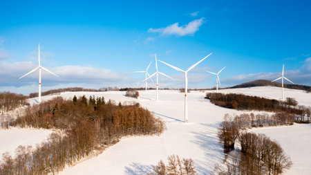 Panoramic view of wind turbine farm on the hill in winter sunny day. Production of renewable energy.