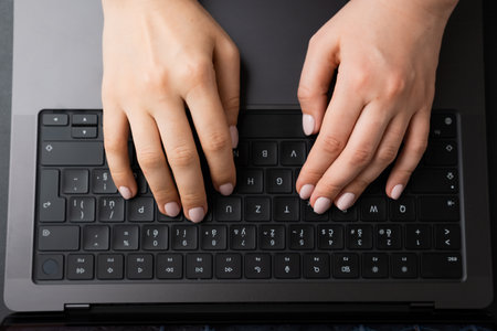 BERLIN, GERMANY - APRIL 14 2024: Female hands on the black keyboard, top view.