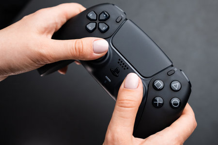 BERLIN , GERMANY - FEBRUARY 14 2024: Nex generation game controller in womans hand on the black...