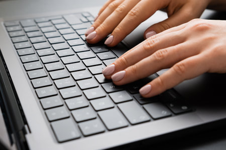 BERLIN, GERMANY - APRIL 14 2024: Female hand working on a laptop keyboard. Business office workplace...