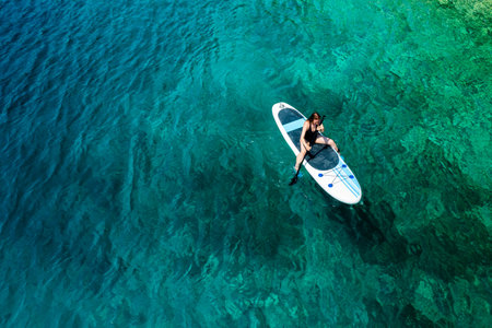 Woman navigating on the paddleboard in the sea at sunset.の写真素材