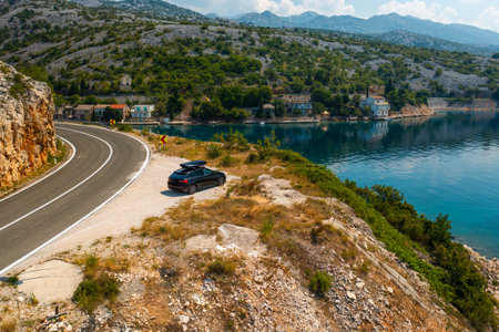 Aerial view of car with a roof box stands on the side of a cliff and beautiful rocks in the backgroundの写真素材