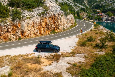 Car with a roof box stands on the side of a cliff and beautiful rocks in the backgroundの写真素材