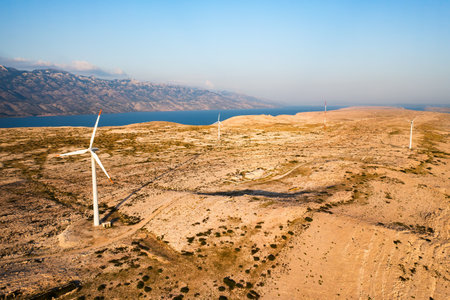 Innovative wind turbines rotate generating clean energy on Pag Island at twilight. Modern technology provides sustainable source of power in Croatiaの写真素材